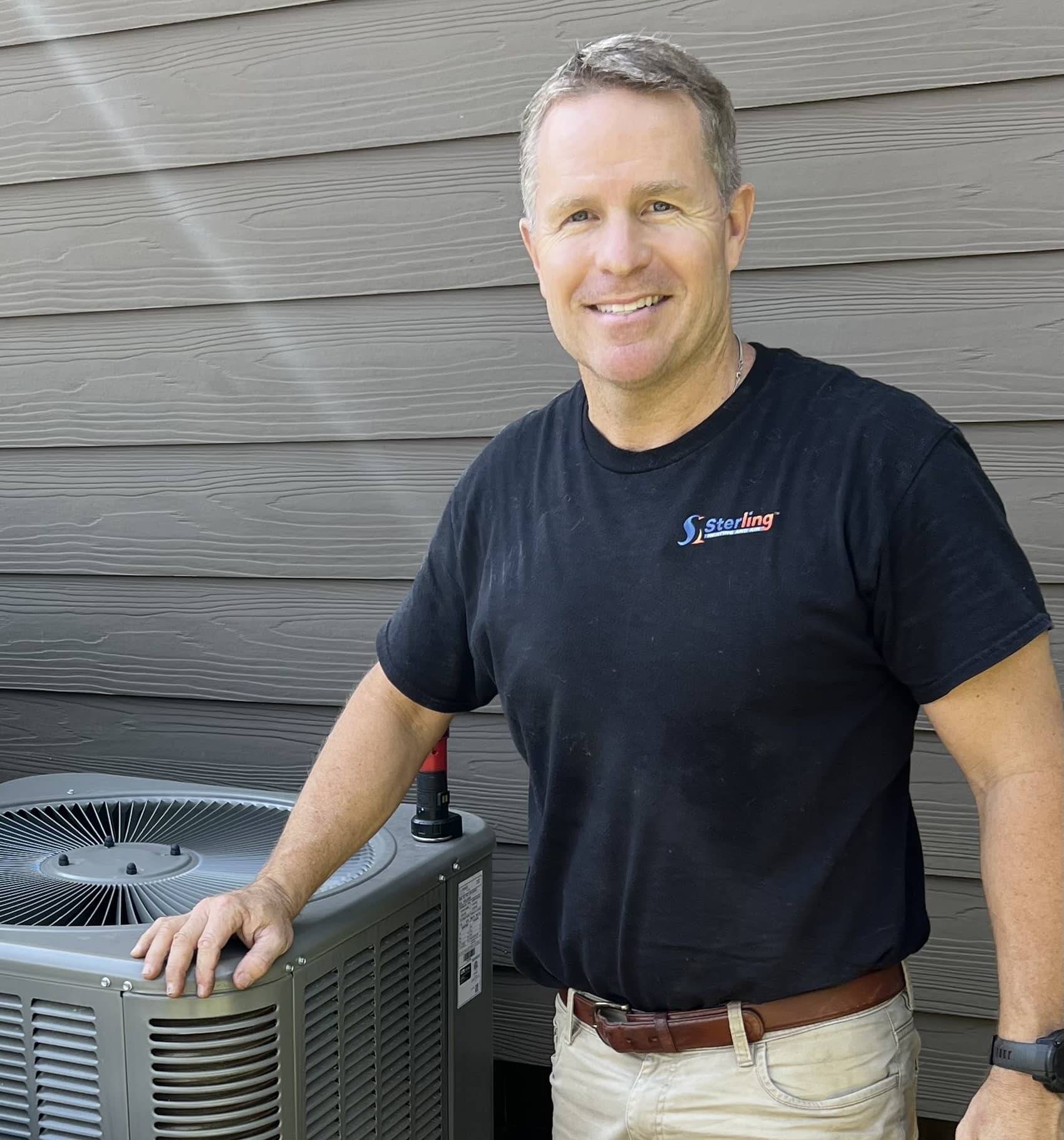 Technician standing by air conditioning unit outdoors.
